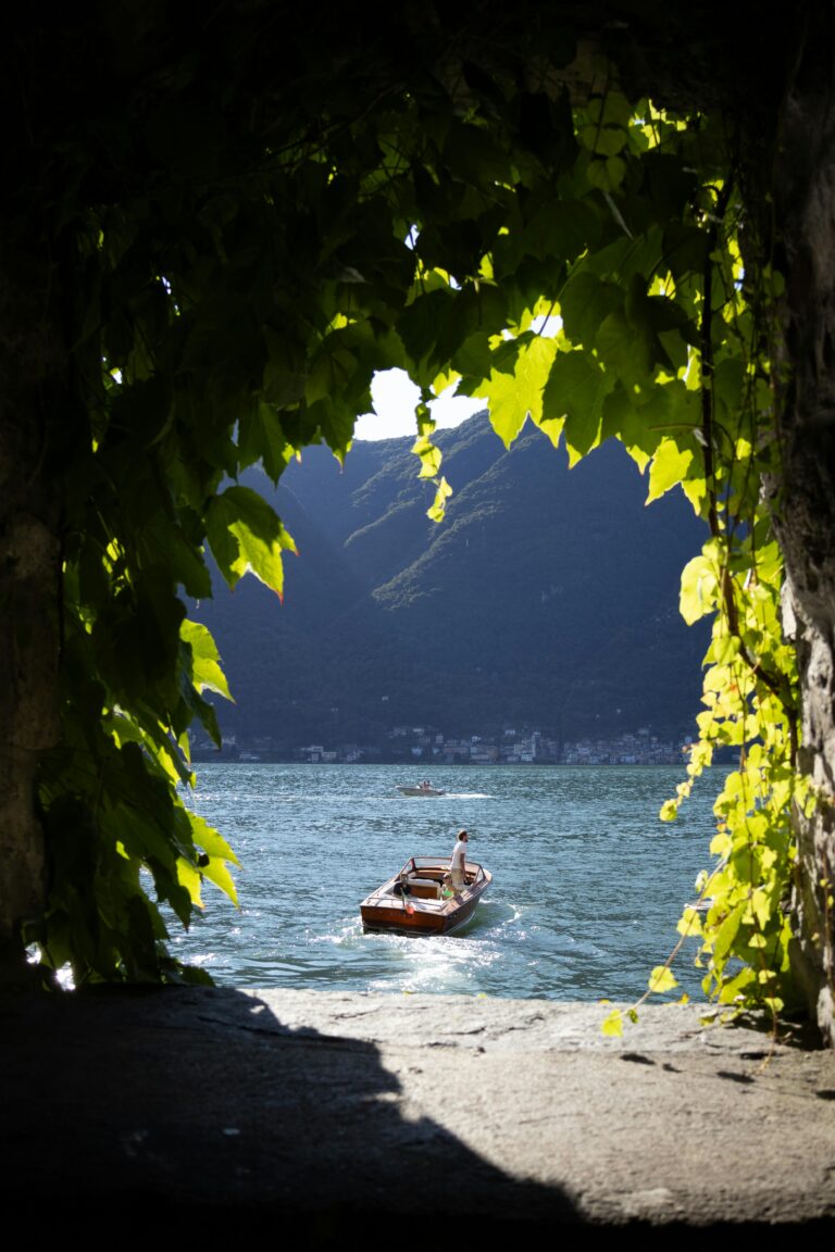 A serene wooden boat on a picturesque lake framed by lush greenery.