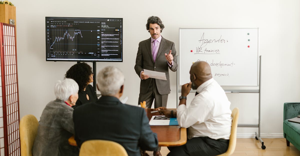 A corporate professional presents market data during a team meeting in an office setting.