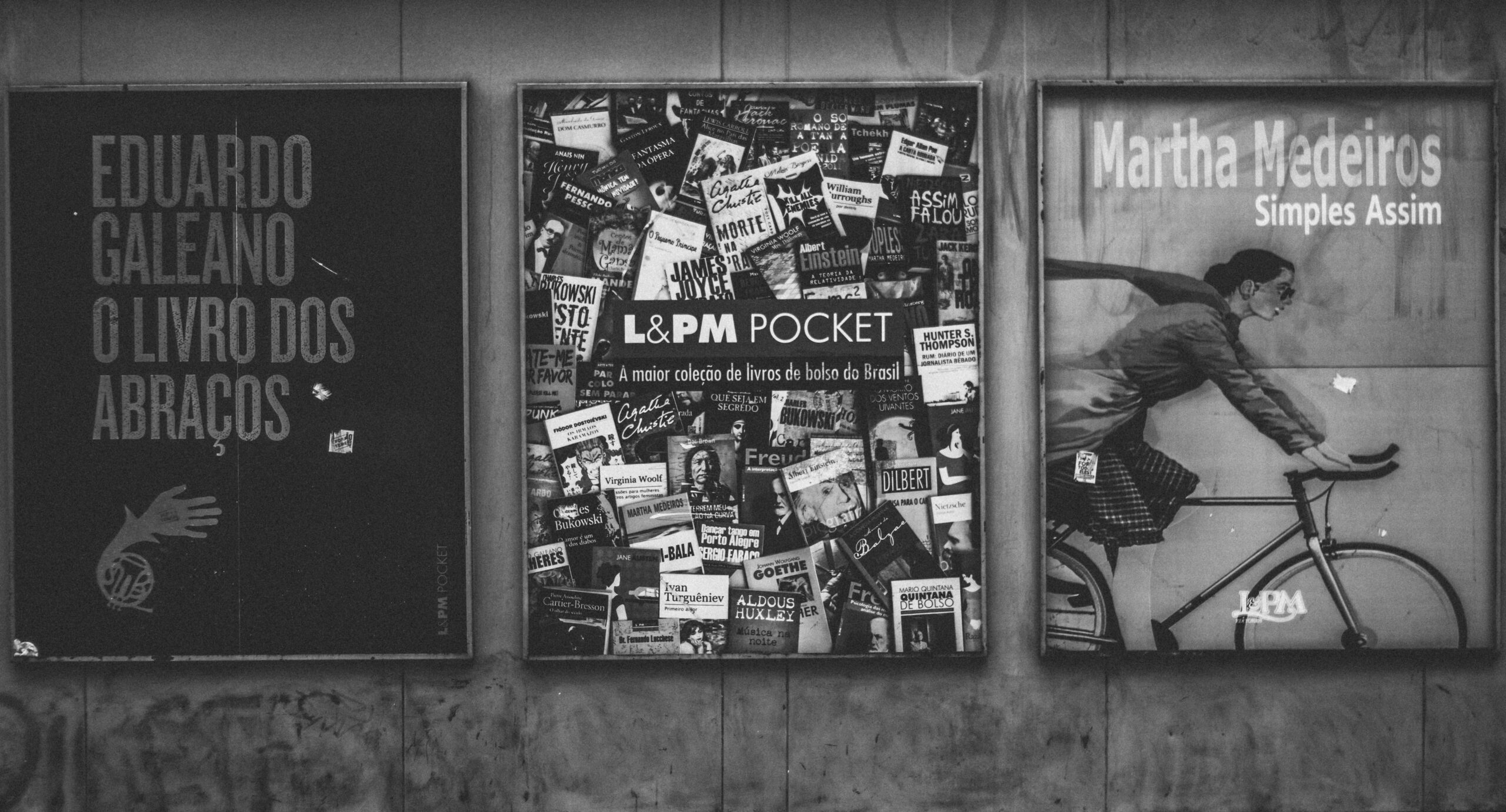 Black and white image of a wall with urban book posters and artistic design.